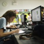 Caucasian woman writing at computer room