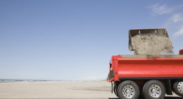 54657,Truck shoveling sand on beach