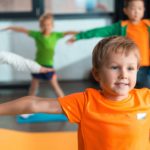 Selective focus of multiethnic kids doing exercise with outstretched hands in sports center