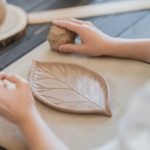 Woman decorating handmade pottery plate close-up